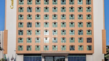 Um hotel com vários andares, fachada moderna, muitas janelas e entrada destacada.