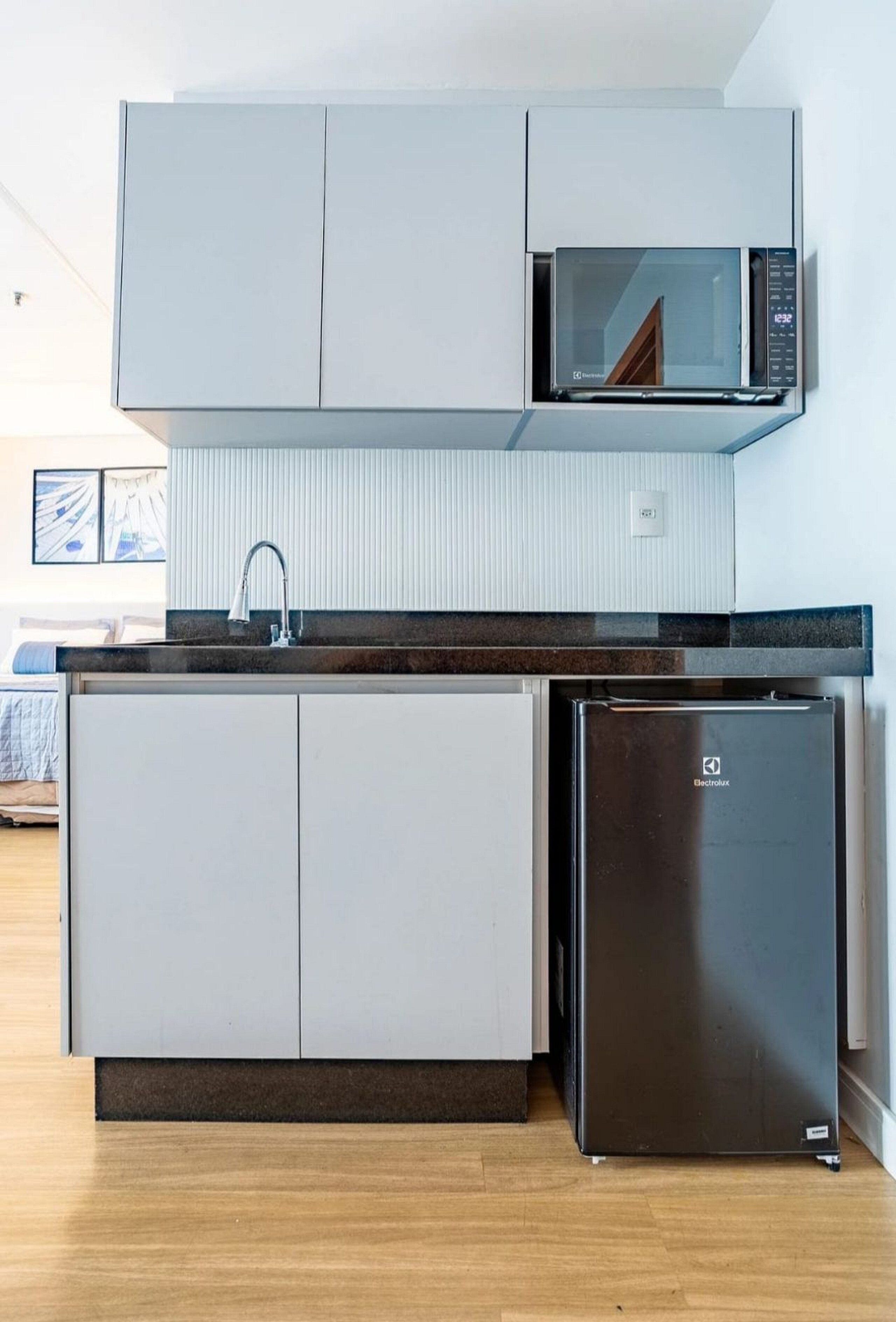 Cocina pequeña equipada con microondas, refrigerador y pileta.