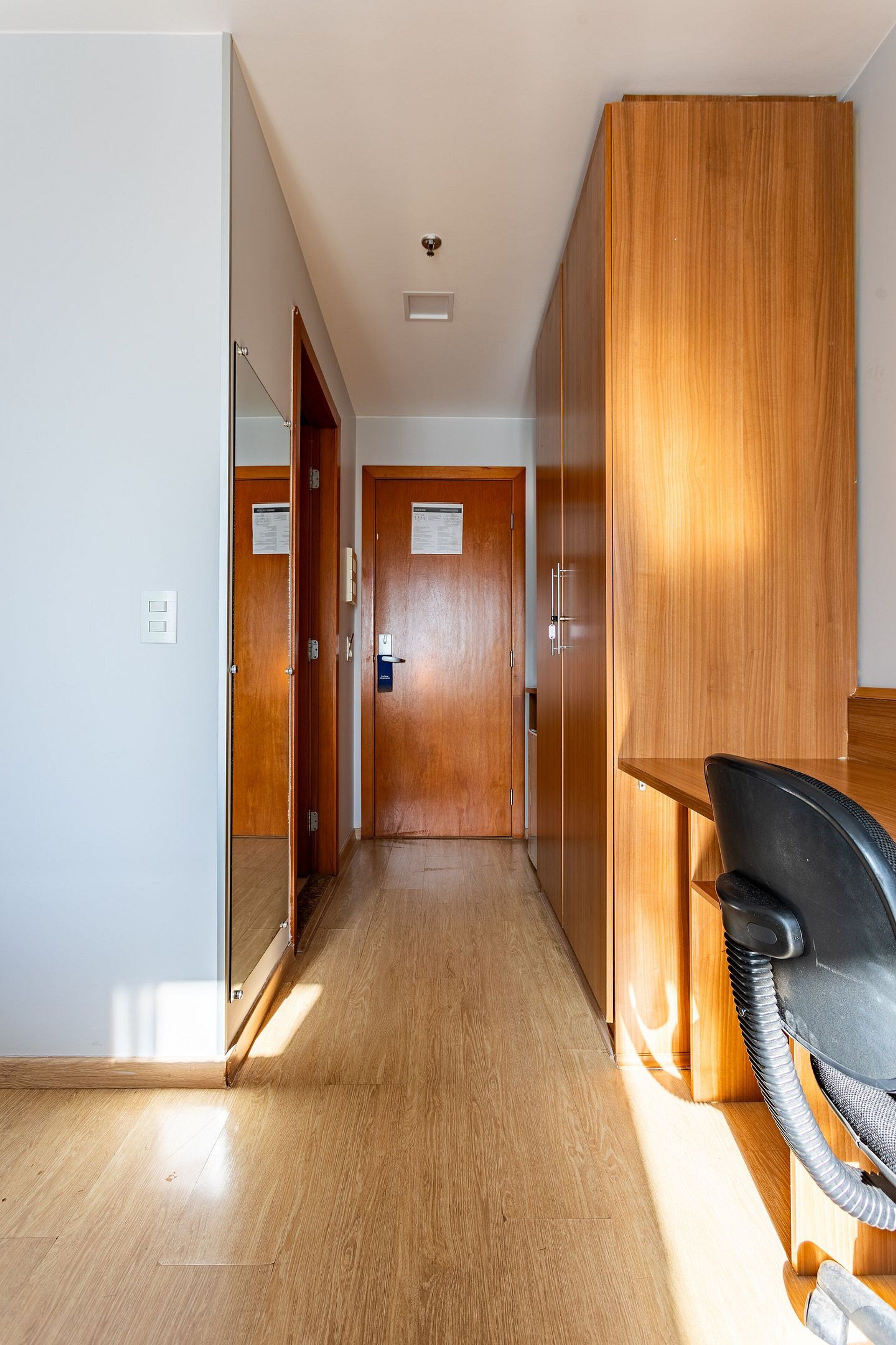 A hallway with wooden doors, a desk with a chair, and a vacuum cleaner.