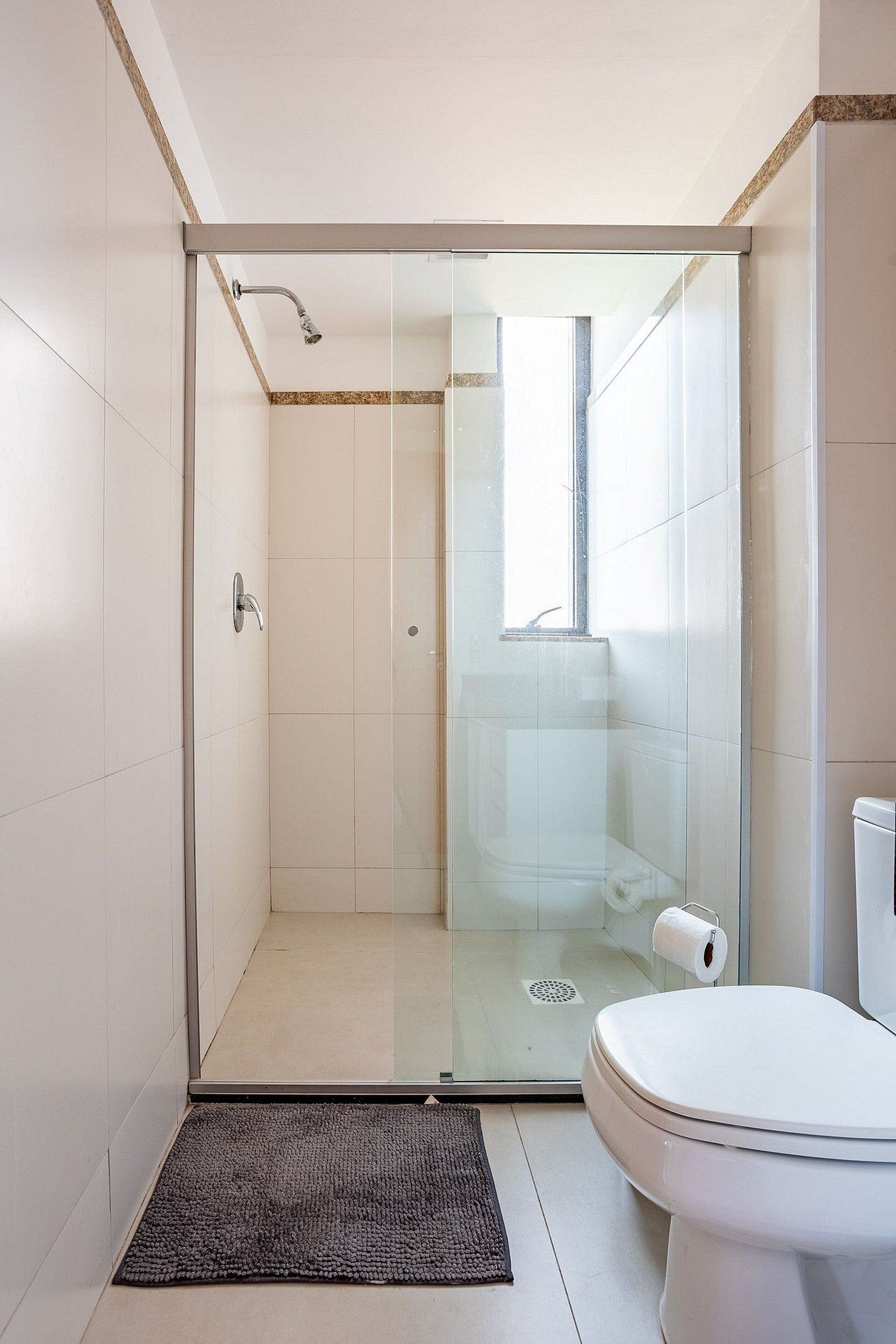 Un baño moderno con cabina de ducha de vidrio, inodoro y un rollo de papel higiénico a la vista.