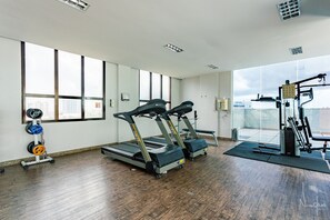 Et træningscenter med løbebånd, vægtstativ og træningsudstyr.