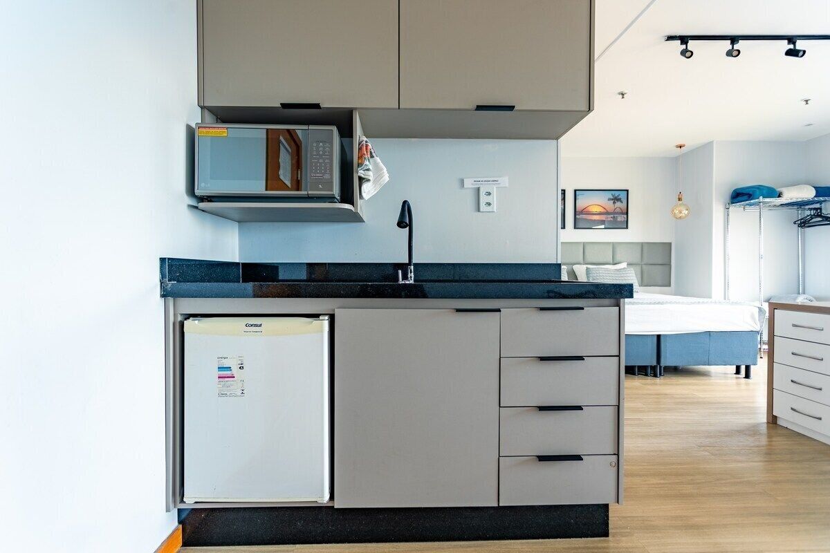 A compact kitchen with a microwave, refrigerator, and a small sink.