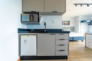 A compact kitchen with a microwave, refrigerator, and a small sink. - Apartamento no hotel Comfort (Taguatinga)