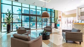 Eine moderne Hotelhalle mit großen Fenstern, bequemen Sitzgelegenheiten und einer Rezeption.
