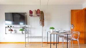 A modern kitchen with a dining area, a TV mounted on the wall, and a wooden door.