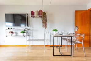 A modern kitchen with a dining area, a TV mounted on the wall, and a wooden door. - Apartamento no hotel Comfort (Taguatinga)
