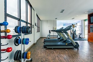 Un gimnasio con cintas de correr, jaulas de pesas y equipo de ejercicio.