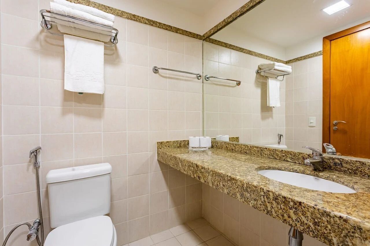 Une salle de bain équipée de toilettes, d’un lavabo et de porte-serviettes.