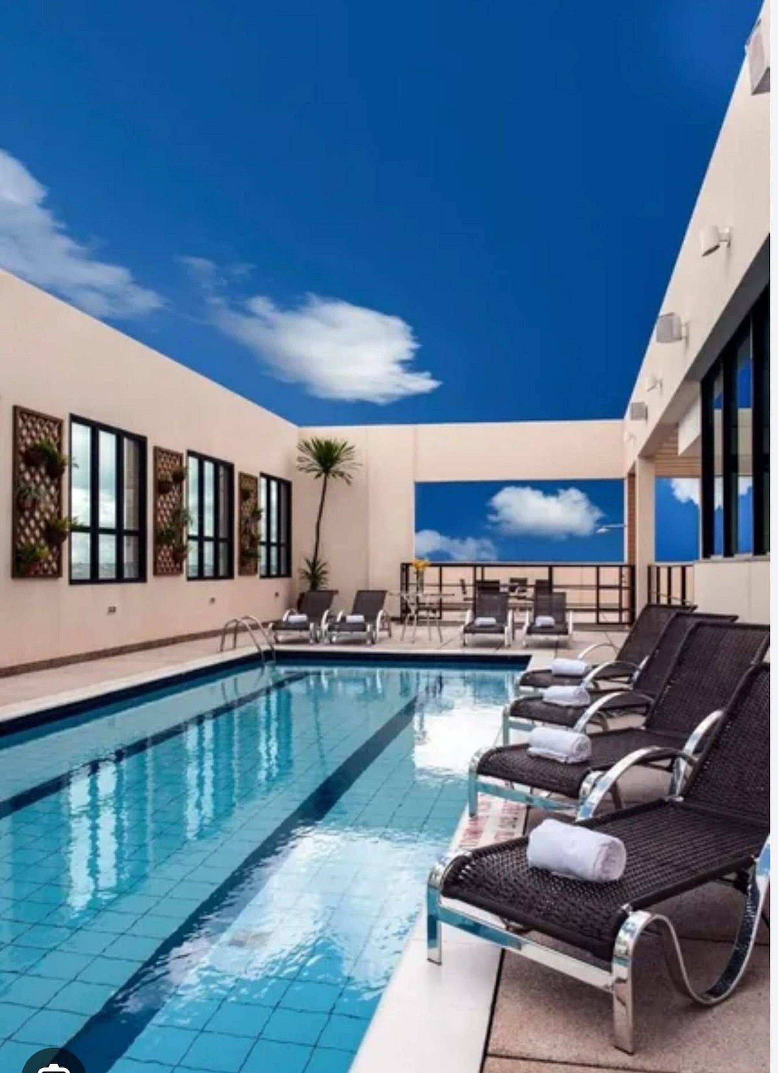 A rooftop pool area with lounge chairs and a clear view of the sky.