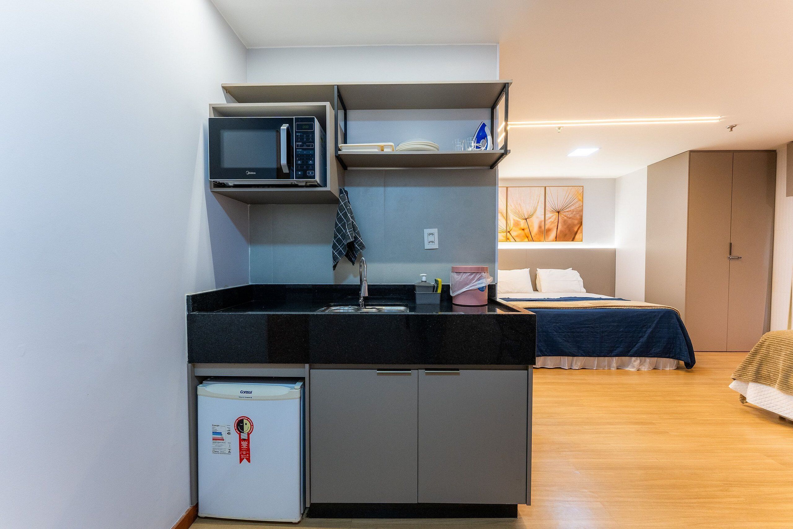 A compact kitchenette with a microwave, refrigerator, and sink.