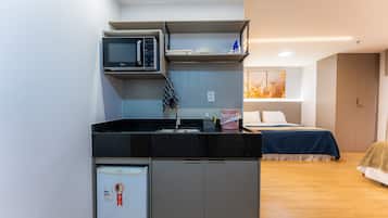 A compact kitchenette with a microwave, refrigerator, and sink.