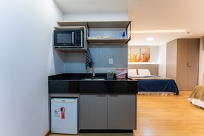 A compact kitchenette with a microwave, refrigerator, and sink. - Apartamento no hotel Comfort (Taguatinga)