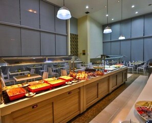 A buffet area with various food items and a seating arrangement with tables and chairs. - Apartamento no hotel Comfort (Taguatinga)