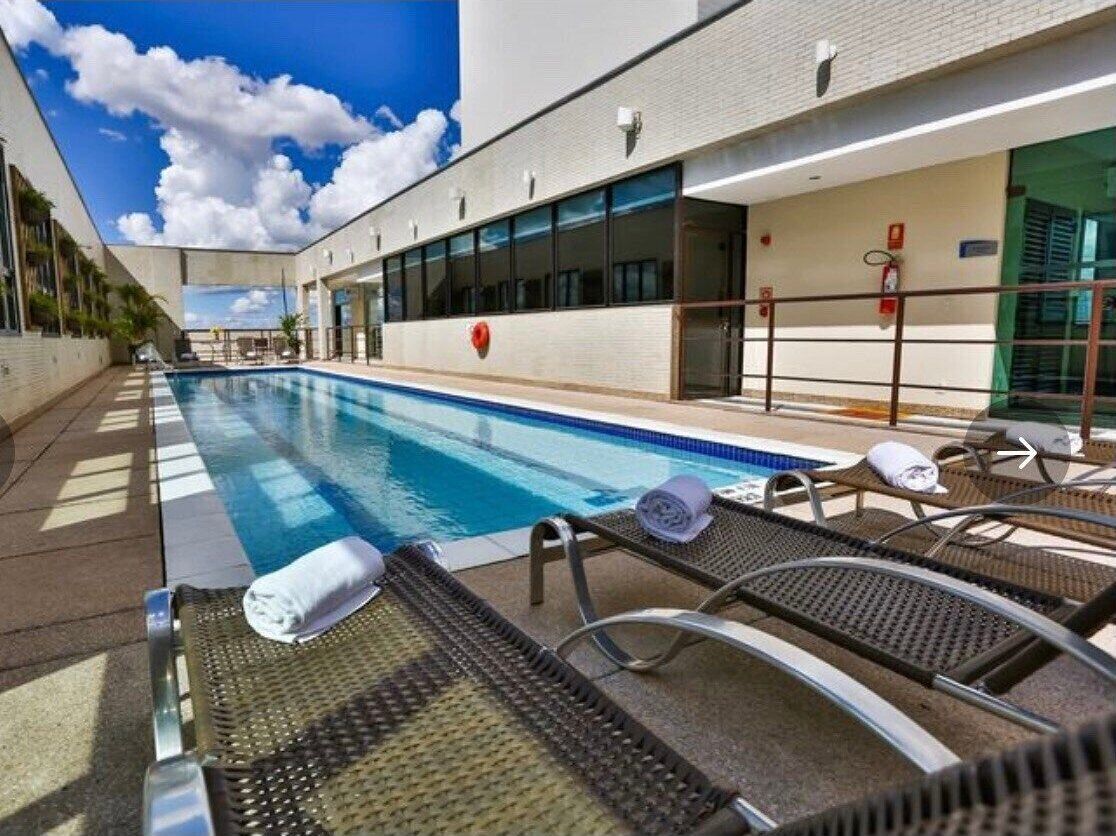 A pool area with lounge chairs and a covered walkway.