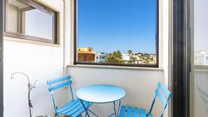 A balcony with a blue table and chairs, a potted plant, and a view of buildings through a window. - 4021 Casa Dolce Margherita by Barbarhouse (Casarano)