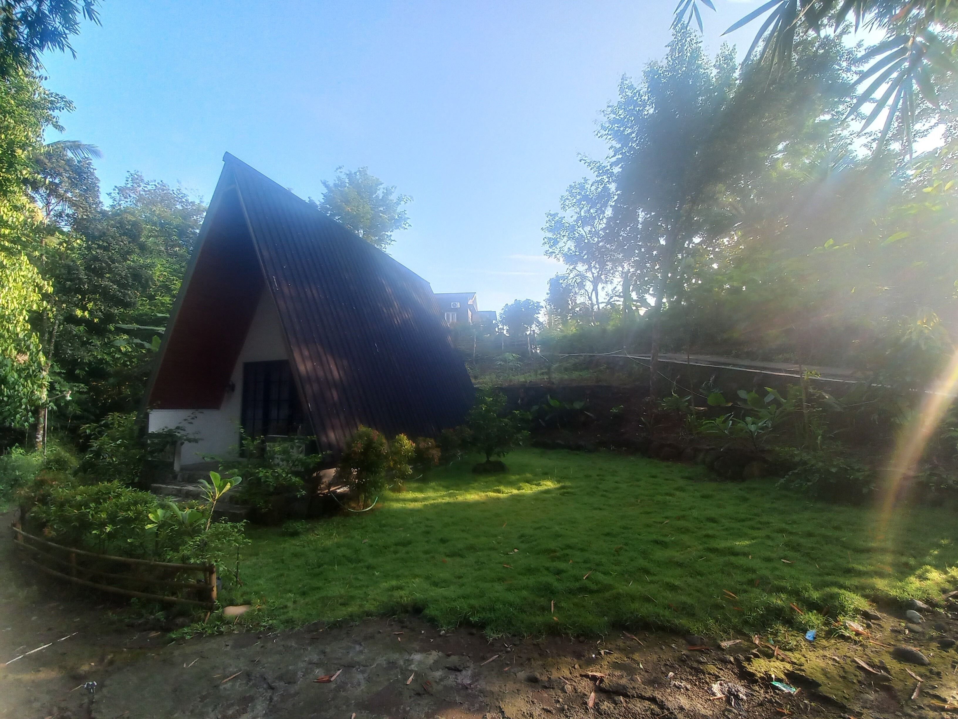 A house with a sloped roof, surrounded by a well-maintained lawn and dense foliage.