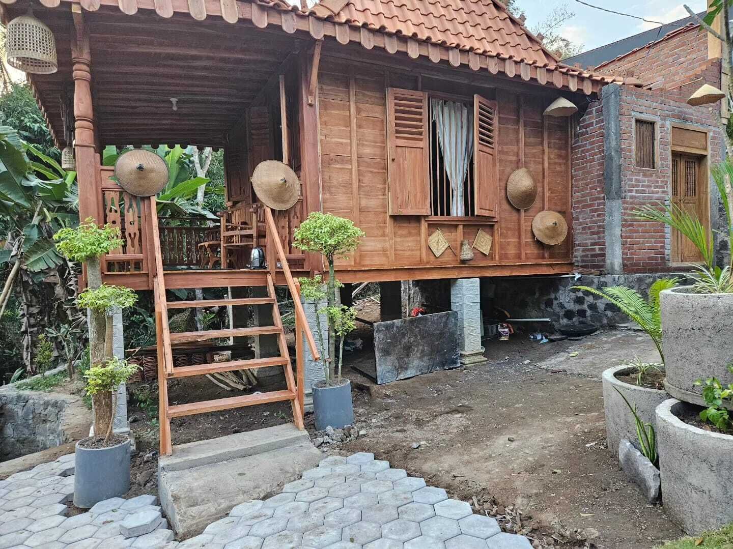 Una casa de fusta tradicional amb teulada de teules, un porxo de fusta i una escala que mena a l'entrada.