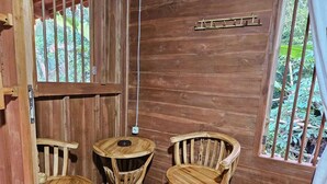 Un interno in legno con un piccolo tavolo e due sedie, una scala e una finestra che si affaccia su del verde.