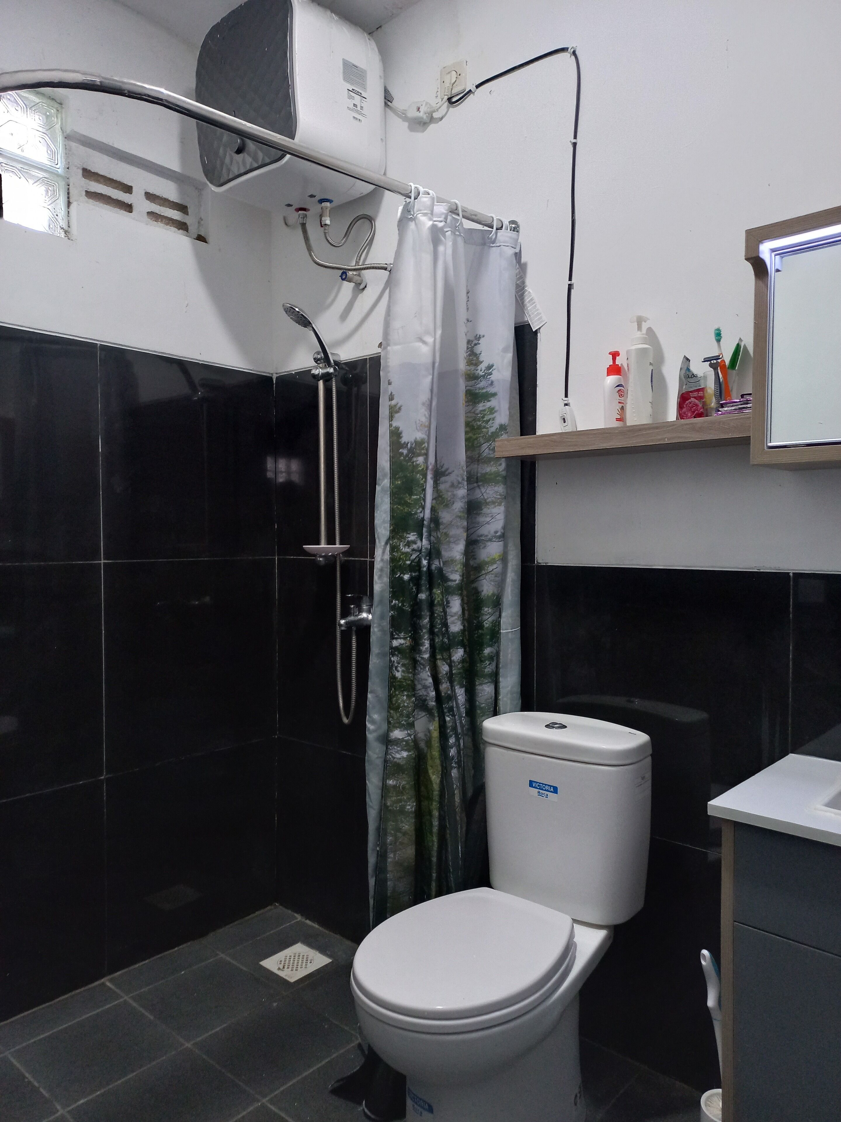 Kylpyhuone, jossa on suihku, wc ja hylly, jossa on hygieniatuotteita.