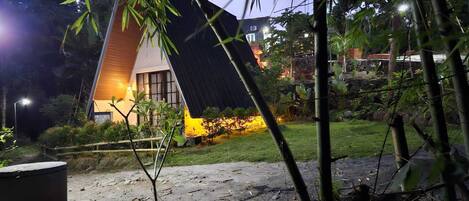 A modern house with a sloped roof, surrounded by bamboo and greenery.