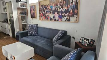 A living room with a grey sofa, a white coffee table, and a framed photo on the wall.