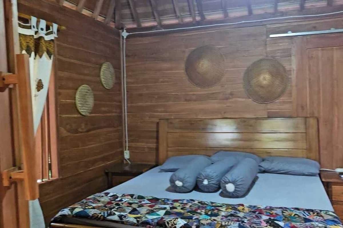 Une pièce en bois avec un lit, une table de chevet et une fenêtre avec des rideaux.