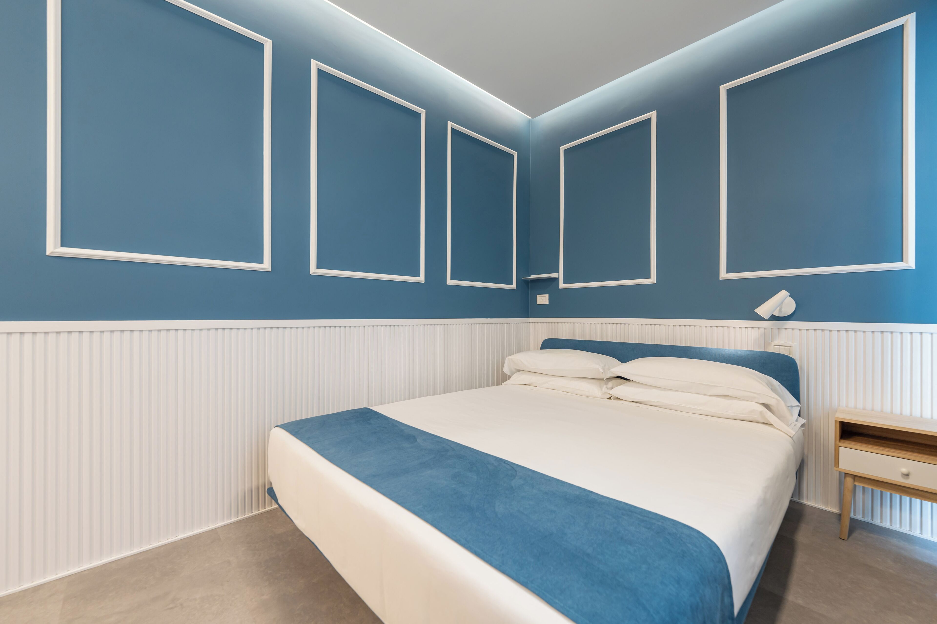 A bedroom with a bed, bedside table, and wall-mounted light fixture.