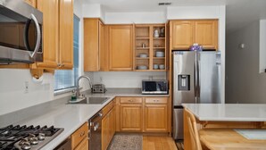 A kitchen with wooden cabinets, a stainless steel refrigerator, a microwave, a stove, and a sink. - San Jose 5BR Home Sleeps 10, Dog Friendly (San Jose)