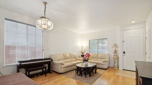 A spacious living room with a piano, a beige sofa, a round coffee table, and a chandelier. - San Jose 5BR Home Sleeps 10, Dog Friendly (San Jose)