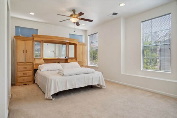 A bedroom with a bed, a wooden wardrobe, a ceiling fan, and large windows. - San Jose 5BR Home Sleeps 10, Dog Friendly (San Jose)
