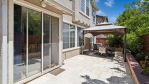 A patio with a covered seating area, a sliding glass door, and a brick pathway. - San Jose 5BR Home Sleeps 10, Dog Friendly (San Jose)