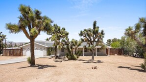 Un quartier résidentiel avec une maison, des palmiers et un ciel dégagé.