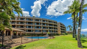 A multi-story hotel with a pool area, surrounded by palm trees and a clear blue sky. - Paki Maui 411 1 Bedroom Condo (Lahaina)