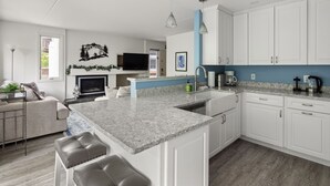 Una cocina moderna con armarios blancos, encimera de granito y una isla integrada con taburetes de bar.