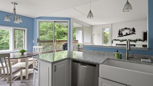 Una cocina moderna con una isla grande, armarios blancos y vistas al exterior a través de amplios ventanales.