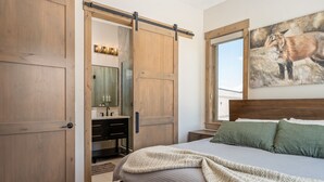 A bedroom with a large bed, a sliding door closet, a bathroom with a mirror, and a painting of a fox on the wall. - Aprez Retreat 3 Bedroom Condo by RedAwning (Winter Park)