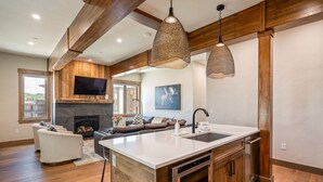 A spacious kitchen with a large island, wooden beams, and pendant lighting. - Aprez Retreat 3 Bedroom Condo by RedAwning (Winter Park)