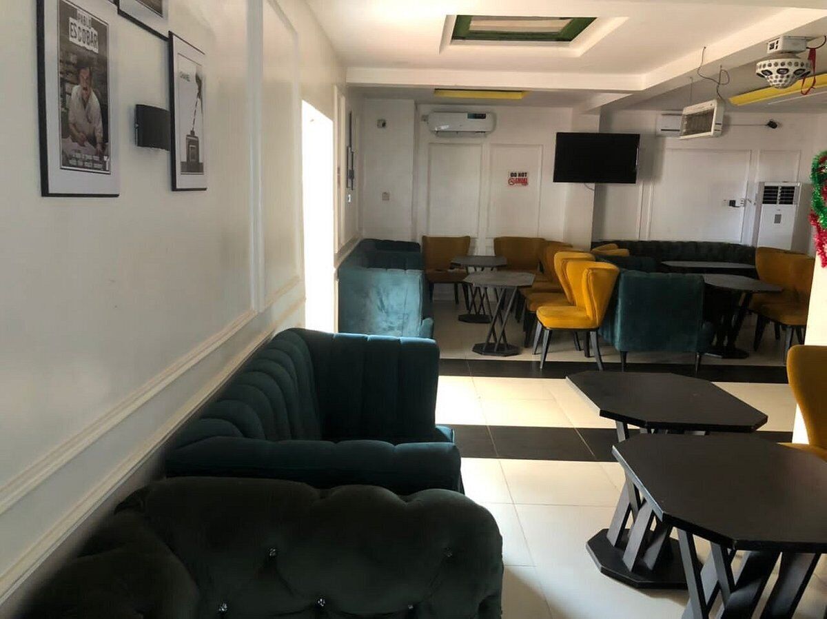 A hotel lobby with a sofa, chairs, tables, and a TV.