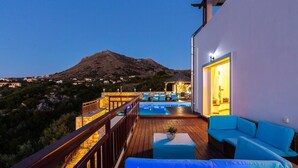 A deck with a pool, outdoor seating, and a mountain view.