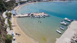 A coastal beach with a marina, beach umbrellas, and boats.