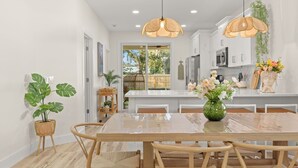 Une cuisine moderne avec des meubles blancs, un îlot central et des luminaires suspendus.