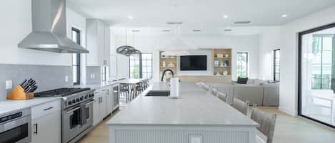 Una cocina moderna con una isla central, electrodomésticos de acero inoxidable y un ventanal grande.