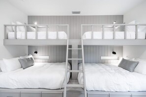 Une chambre avec un lit superposé, comportant deux lits, chacun avec des oreillers et une table de chevet.