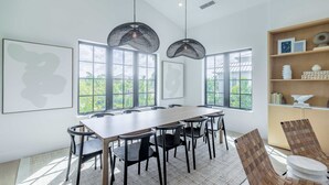 Una sala de reuniones moderna con una mesa larga, sillas y dos lámparas colgantes.