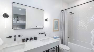 Une salle de bain moderne avec un grand miroir, deux lavabos, une douche et des toilettes.