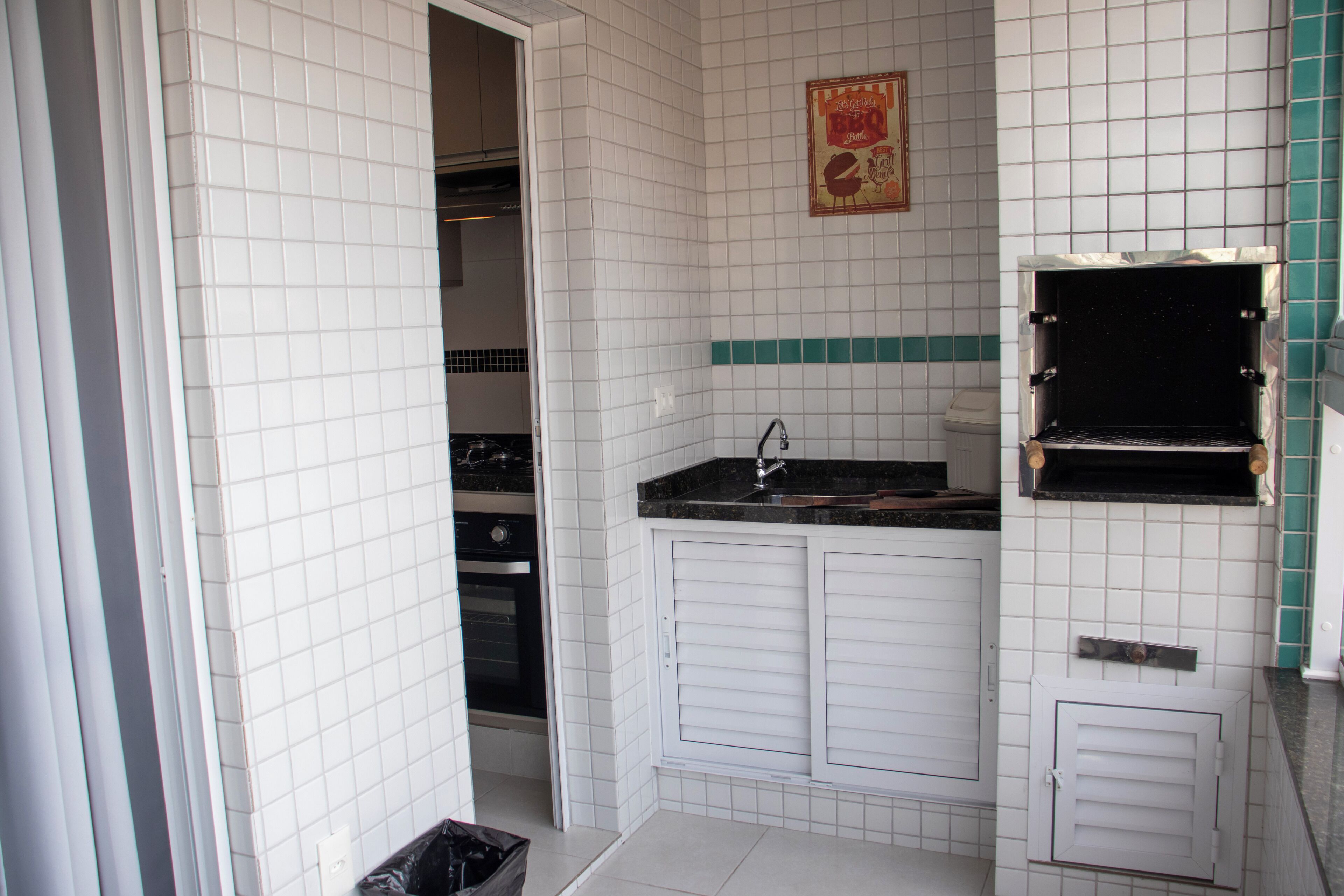 Una cucina compatta con pareti piastrellate di bianco, un piano di lavoro nero e un forno integrato.