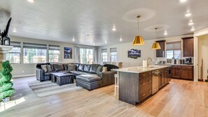 Ein geräumiges Wohnzimmer mit einer großen, bogenförmigen Eckcouch, einer Küche mit modernen Geräten und einem Essbereich mit einer großzügigen Kücheninsel.