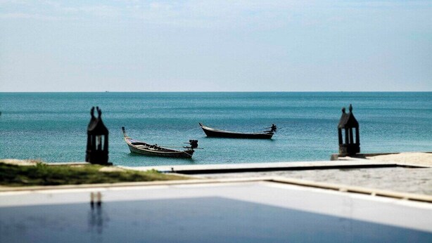 Vista do mar com barcos e duas lanternas na praia.