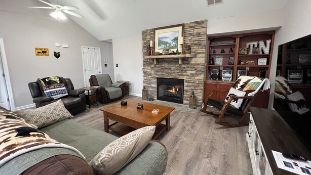 A living room with a fireplace, leather sofas, a coffee table, and a stone accent wall. - Christmas Condo w/ garage just off the Parkway in Pigeon Forge, TN (Pigeon Forge)