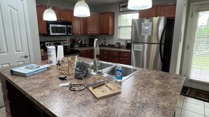 A kitchen with granite countertops, stainless steel appliances, wooden cabinets, and pendant lighting. - Christmas Condo w/ garage just off the Parkway in Pigeon Forge, TN (Pigeon Forge)